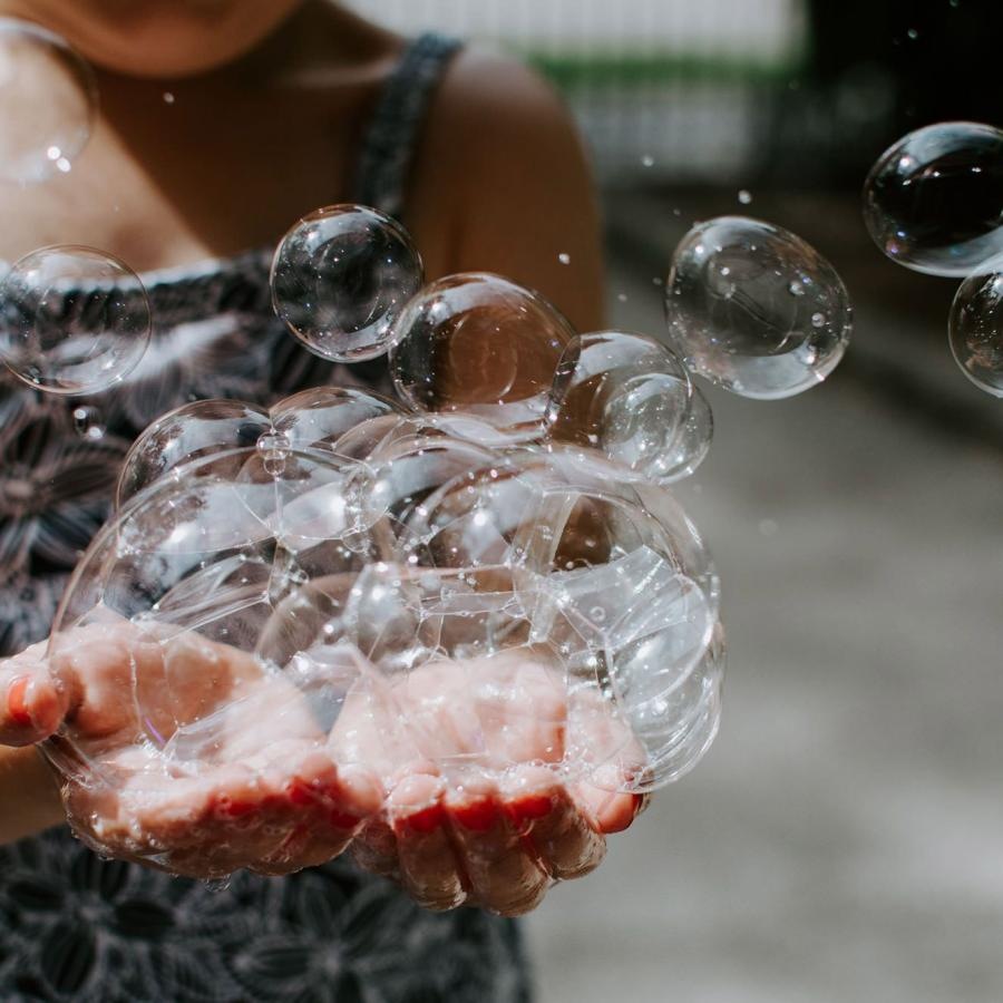 child holding bubbles in her hand as some float away